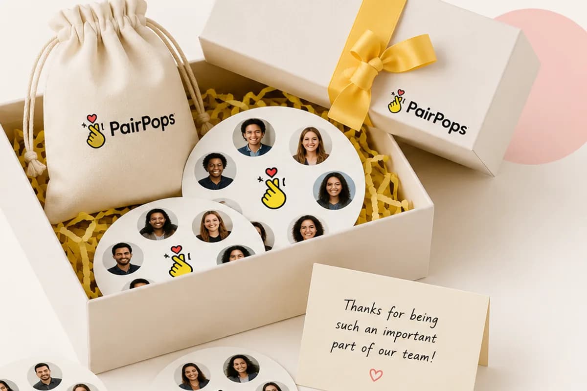 A PairPops gift box with a drawstring bag, ribbon-tied packaging, and matching discs featuring team photos, alongside a thank-you card